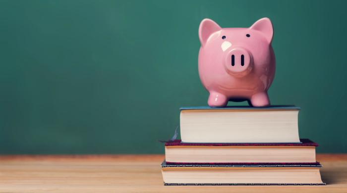 Piggy bank on top of school textbooks