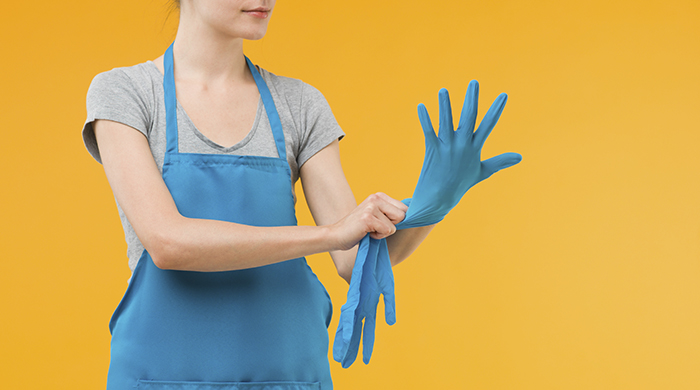 Woman Putting on Blue Kitchen Gloves