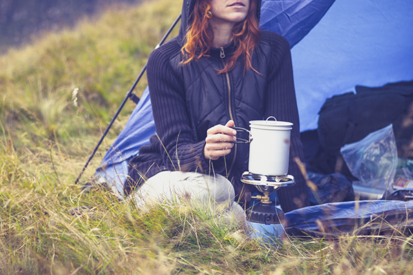 Woman camping and cooking with portable gas stove