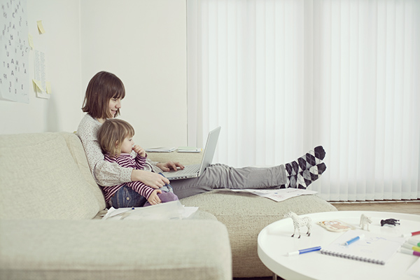 Side view of a mother and daughter with laptop in the living room