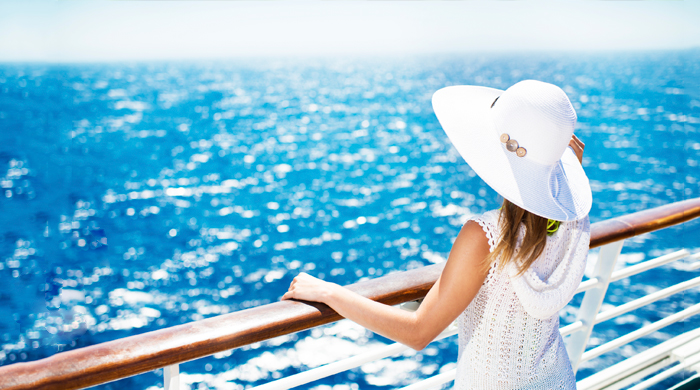 Woman in white hat standing on the deck of a cruise ship