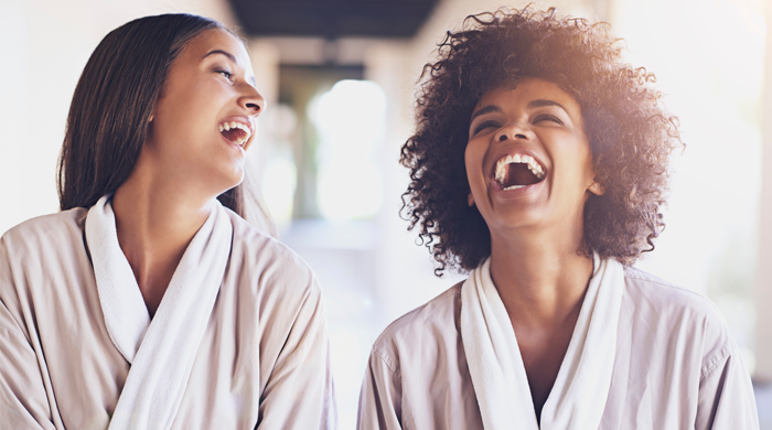 Two female friends laughing in bathrobes