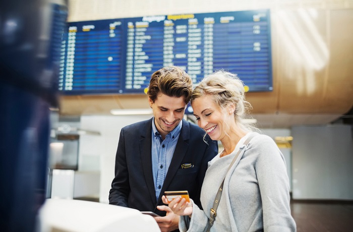 Couple at airport booking flight with credit card