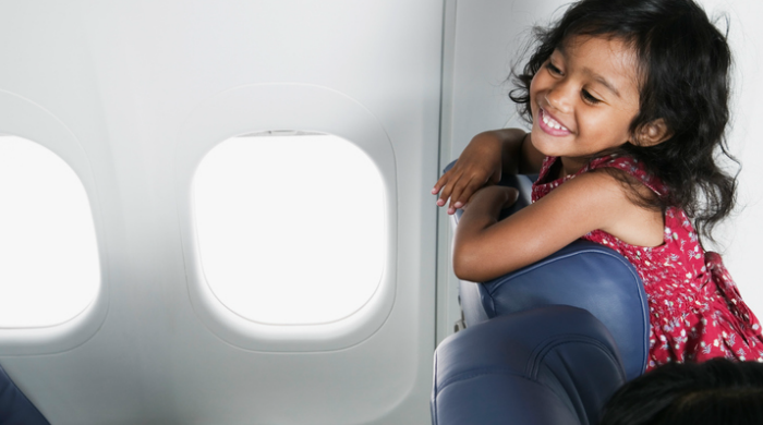 Little girl looking over her seat in an airplane