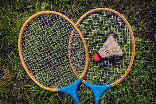 Vintage badminton rackets and shuttercock lying in grass