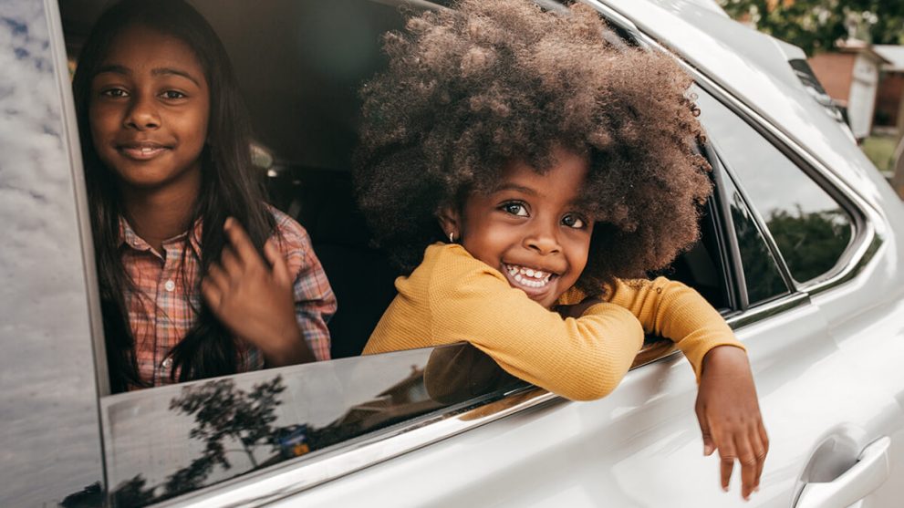 Child smiling out of a car window