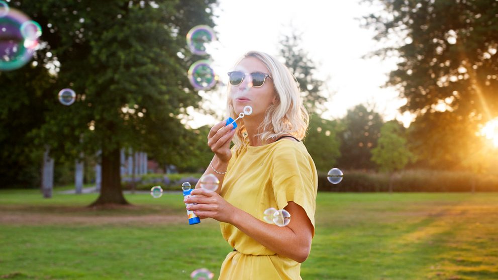 Girl in a yellow dress blowing bubbles