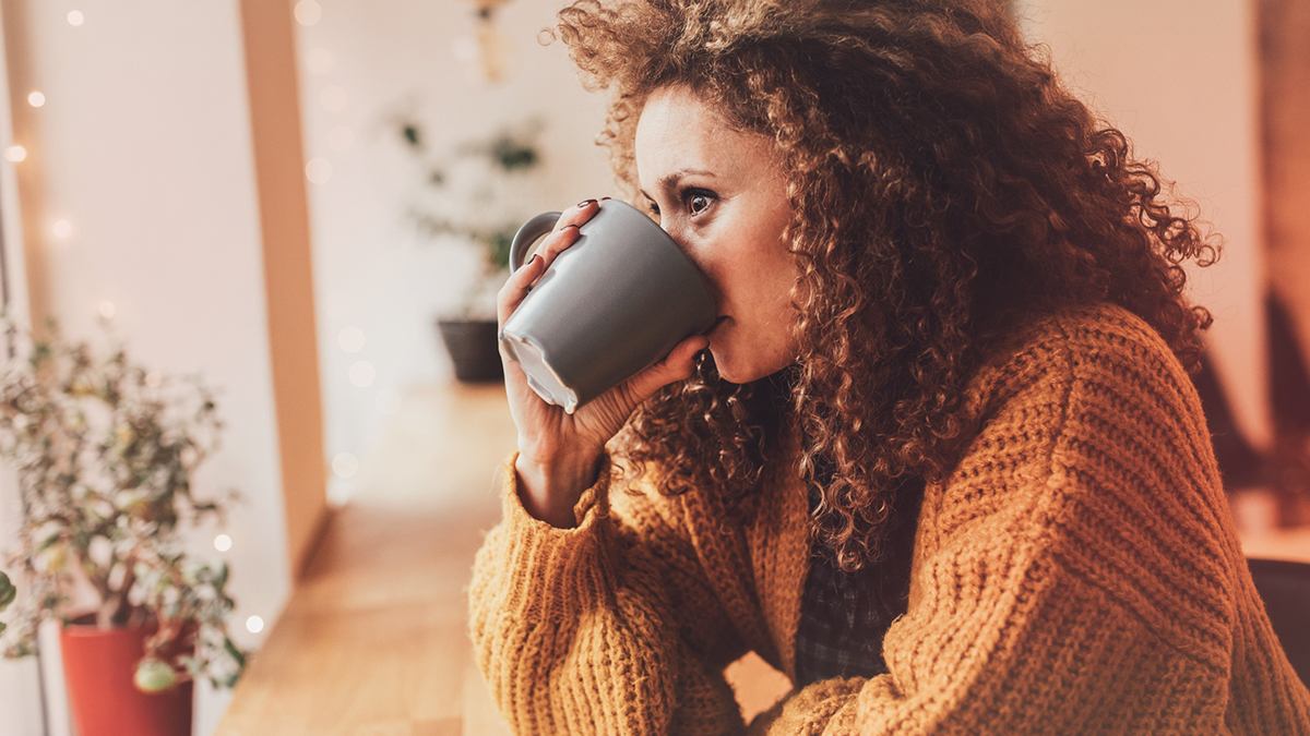 woman wearing a cardigan drinking from a mug